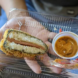a person holding a sandwich and dipping sauce