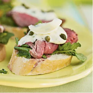 Sliced tenderloin atop a baguette slice with arugula, citrus aioli, capers, and a parmesan shaving.