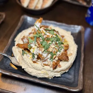 Loaded hummus - slow-roasted chicken and lamb shawarma over hummus, pine nuts, amba, tahini, served with pita