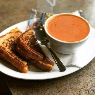 Roasted Red Pepper Tomato Bisque soup with a side of grilled cheddar cheese on white bread.