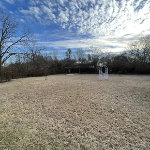 Outdoor wedding ceremony area with pergola. White hydrangeas bloom behind the pergola in the spring.