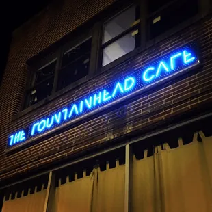 a neon sign on a brick building