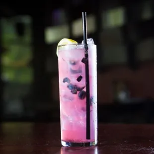 a pink cocktail with a lemon wedge