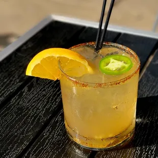 a cocktail with a slice of jalapeno