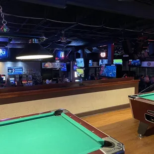 Pool tables at the top of the stairs toward the back of the bar.