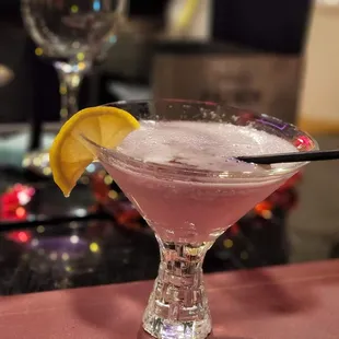 a pink cocktail with a lemon wedge