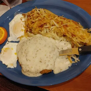Country fried steak with eggs over easy hash browns and toast.