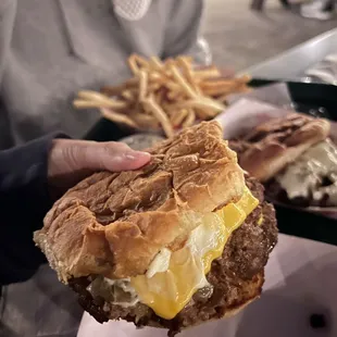 a person holding a sandwich and french fries