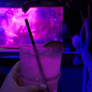 a person holding a drink in front of a tv