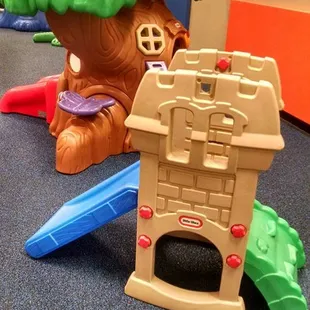 a play area with a tree house and a slide