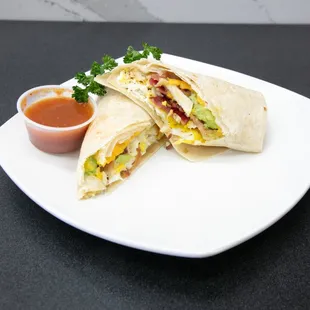 a burrito cut in half with a side of sauce