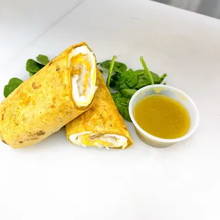 two burritos and a small bowl of sauce