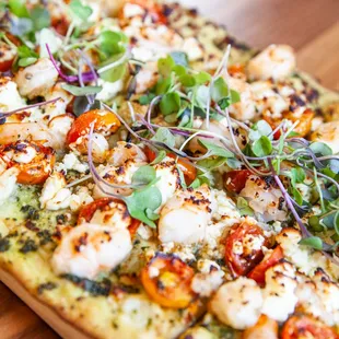 a flatbread pizza with shrimp and tomatoes