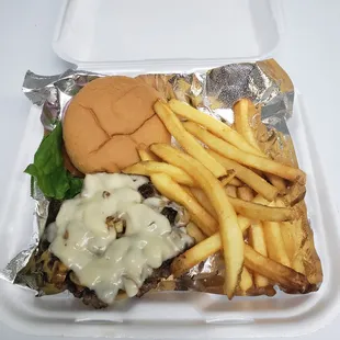a hamburger and french fries in a styrofoam container