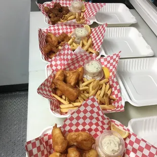  a row of trays of fried fish and fries