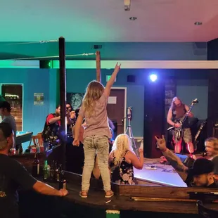 a woman standing on a table with her arms in the air