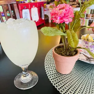 a glass of lemonade next to a flower pot