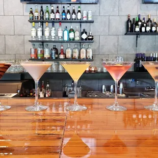 a row of cocktails on a bar