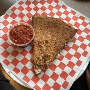 a slice of pizza on a red and white checkered paper