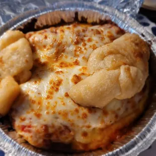 Lasagna (to-go) comes with garlic knots on top.
