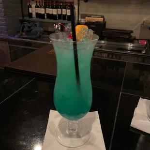 a glass of blue liquid with a straw