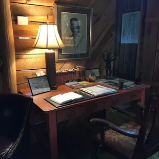 Writing table in the cabin next to a window that looks upon a lush view of tree leaves