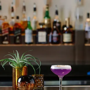 a purple cocktail sitting on a bar