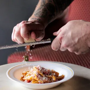 a man grating pasta on a plate