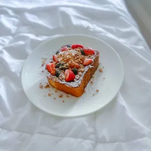a plate of french toast with strawberries and powdered sugar