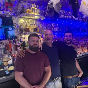 three men standing in front of a bar