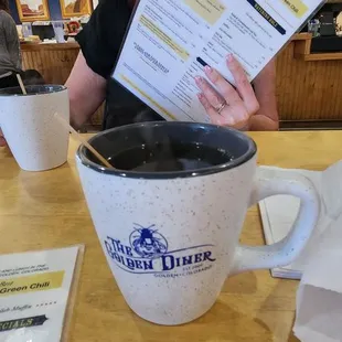 a woman reading a menu in a coffee cup