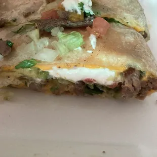 Thick quesadilla with meat, lettuce, cheese, sour cream, avocado and tomato inside. Crispy outside, moist inside.