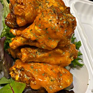 a tray of chicken wings on a bed of lettuce