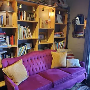 a purple couch in front of a bookshelf