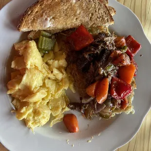 good wives hash - bits of braised beef with veggies and potatoes topped with two eggs scrambled and a side of toast