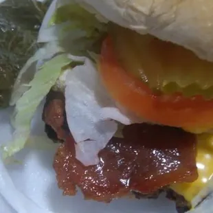 a hamburger with bacon, lettuce, tomato, cheese, and tomato