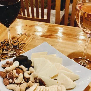 a glass of wine and a plate of cheese and nuts