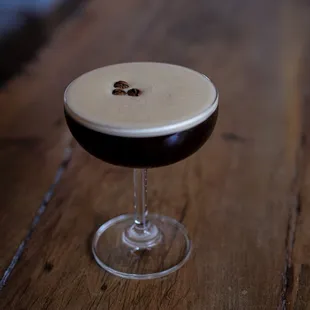 a dark drink in a glass on a wooden table