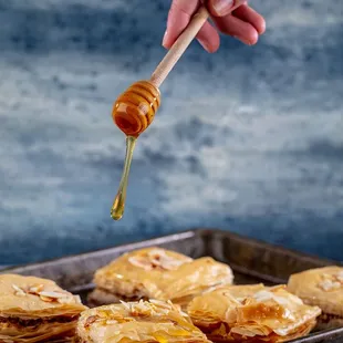 a hand holding a wooden spoon with honey on it