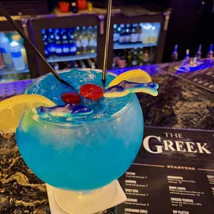 a blue cocktail with a cherry garnish