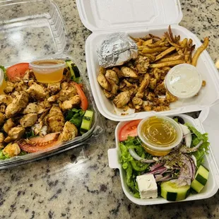 two takeout containers with chicken, salad, and french fries