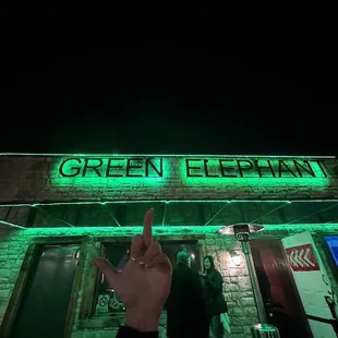 a person pointing at the neon sign