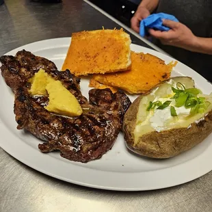 a plate of steak, potatoes, and a baked potato