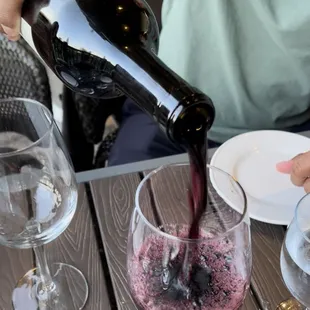 a person pouring wine into a glass