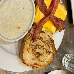 a plate of food with bacon, cheese, and a side of soup