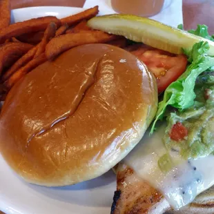 Grilled chicken sandwich topped with guacamole and a side of sweet potato fries