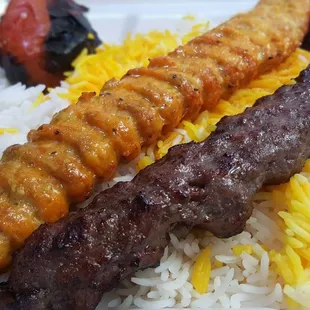 two skewers of meat and rice on a plate