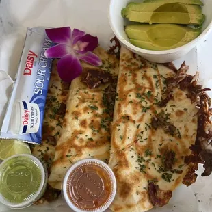 a meal of quesadillas, guacamole, and an avocado