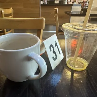 Empty coffee cup and empty orange juice container, consumed during long wait for food.