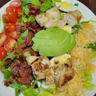 a salad with chicken, bacon, avocado, and tomatoes
